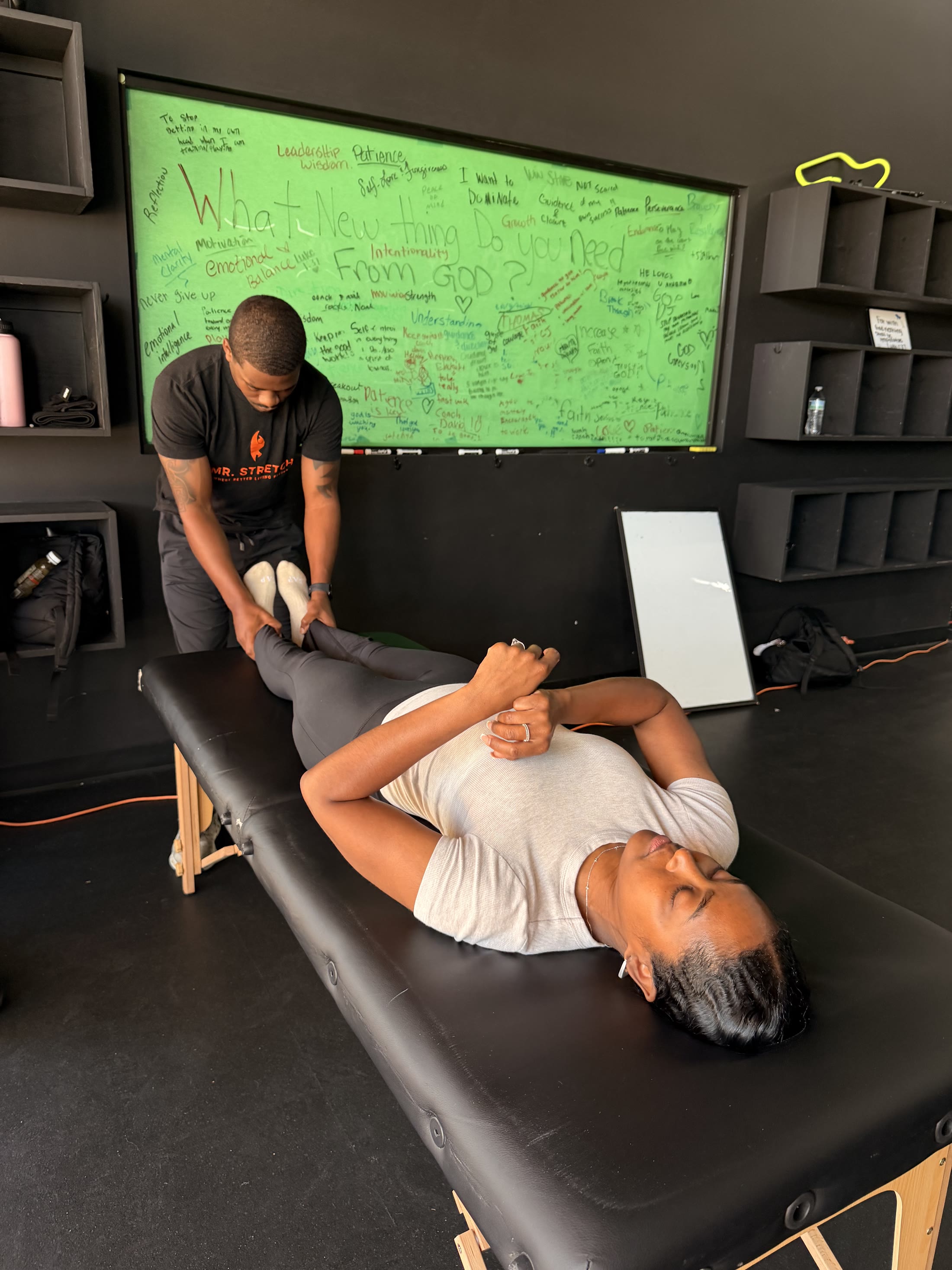 Deveon guiding a client through an assisted leg stretch